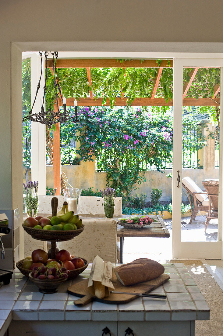 Blick von Landhausküche durch Schiebetüren auf sommerliche überdachte Terrasse