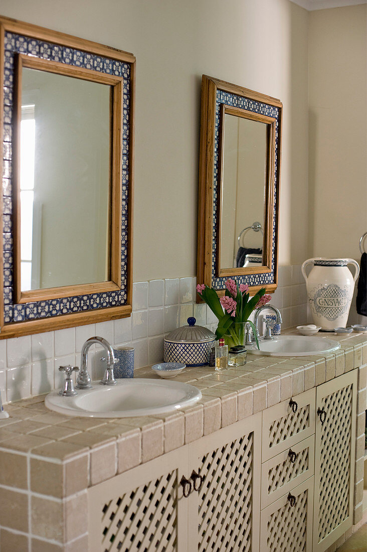 Mosaic-framed mirrors above tiled washstand in country-house-style bathroom