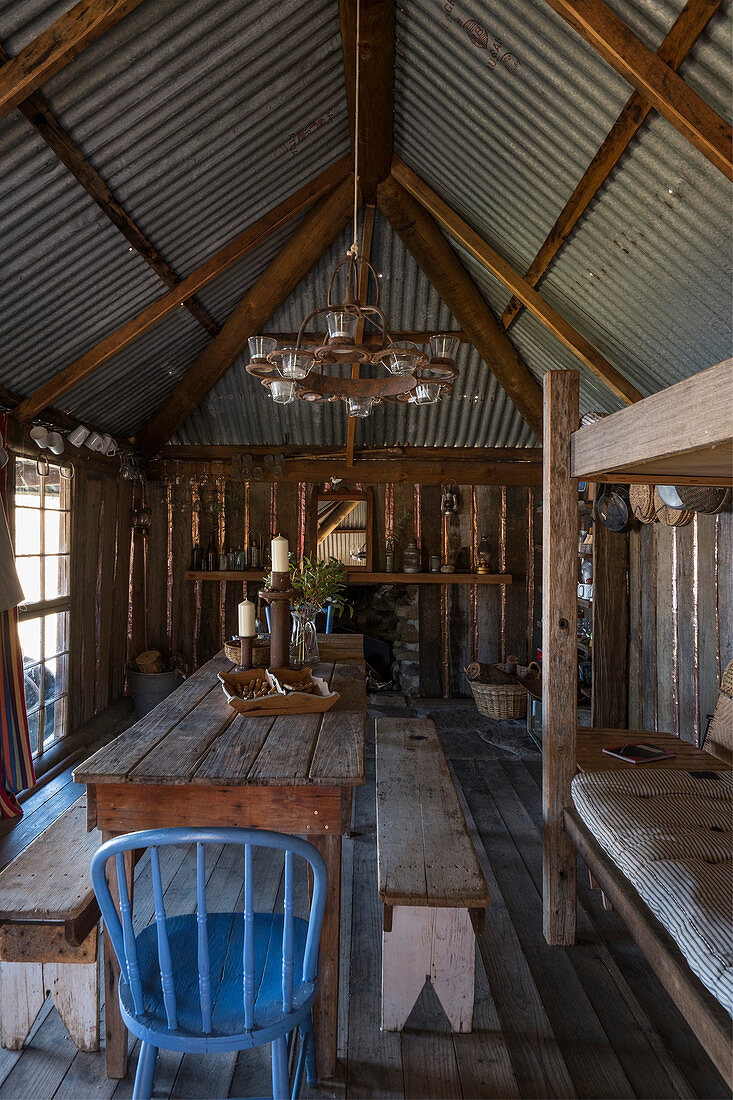 Holztisch mit Bänken und Stühlen in rustikaler Holzhütte