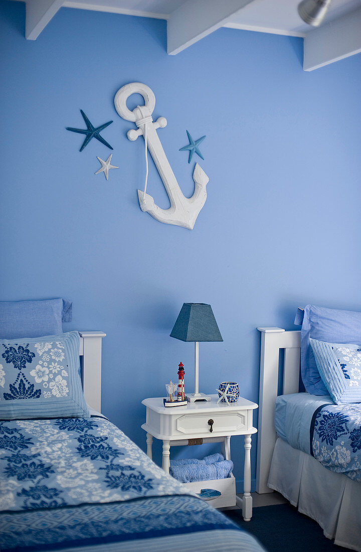 Maritim gestaltetes Schlafzimmer in Blau-Weiß mit Nachttisch zwischen zwei Einzelbetten