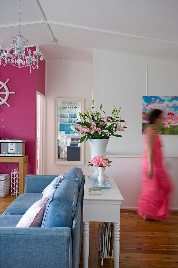 Konsolentisch hinter blauem Sofa in Wohnraum mit pinkfarbenen und weißen Wänden