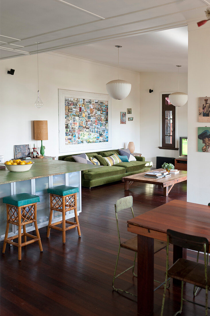 Offener Wohnraum im Vintagestil mit Sofa, Hockern an Frühstückstheke und Esstisch