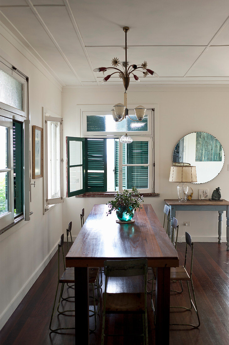 Wohnraum im Vintagestil mit dunklem Holz-Esstisch, Dielenboden und blauen Fensterläden