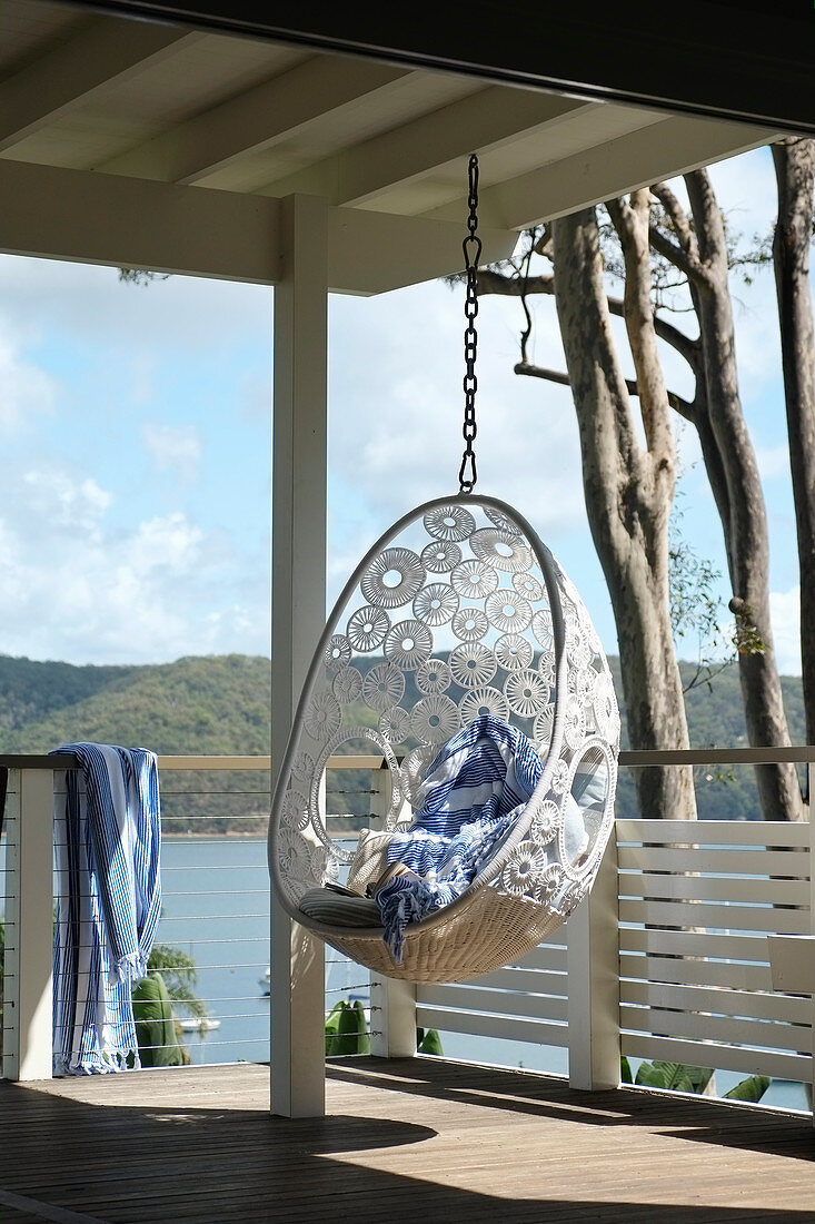 Hanging chair made from white crocheted lace on roofed veranda