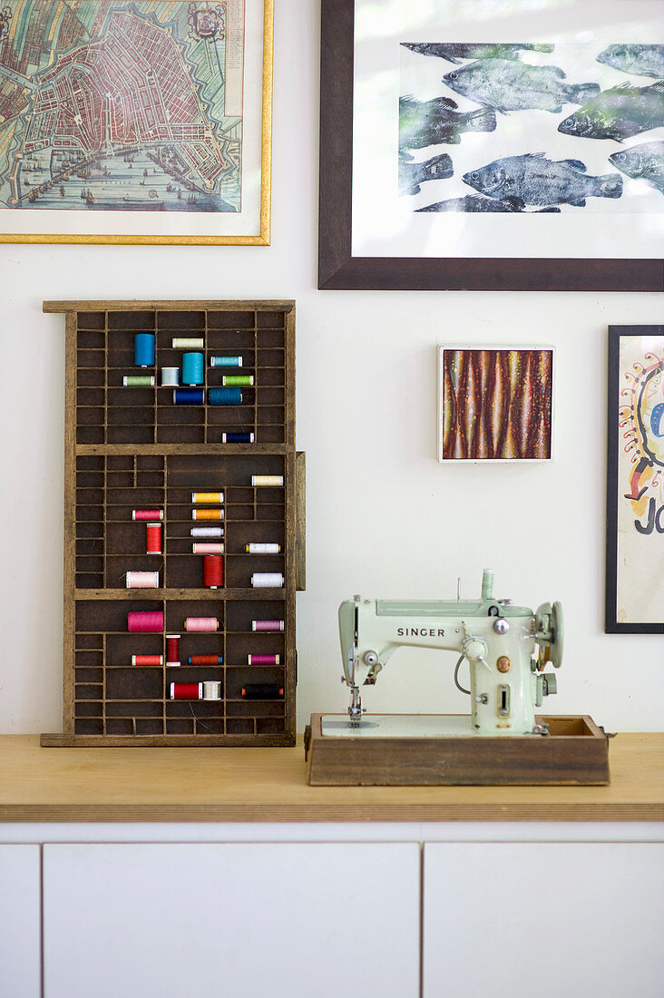 Vintage sewing machine next to wooden letter case used to store reels of thread