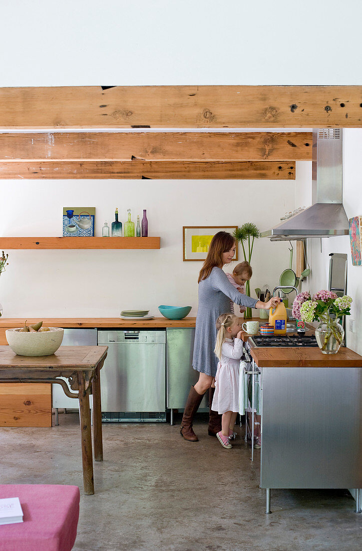 Küche mit Edelstahlfronten und Holzarbeitsplatten in Wohnraum mit Holzbalkendecke