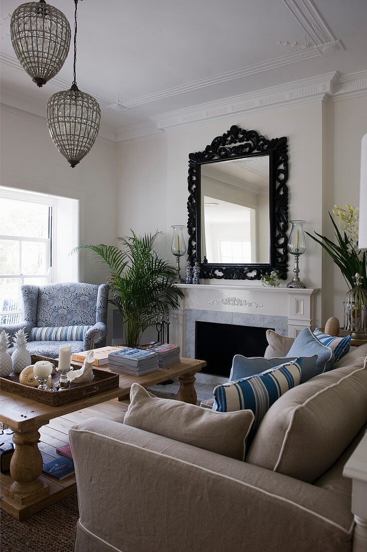 Sitzecke mit beigefarbenem Sofa und blauem Sessel an elegantem weißen Kamin