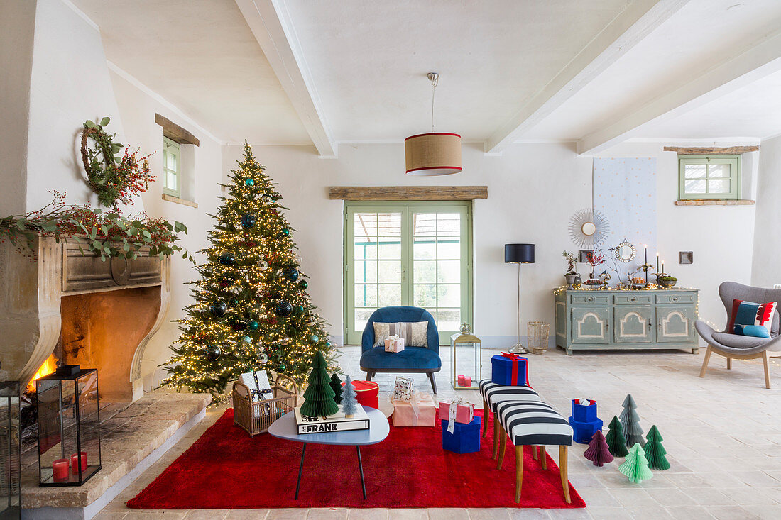 Christmas tree and blue and red furnishings in front of open fireplace