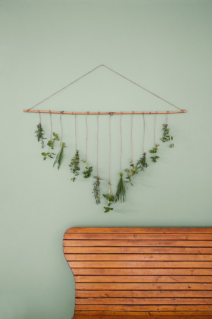 Handmade wall hanging: bunches of herbs hanging from bamboo cane