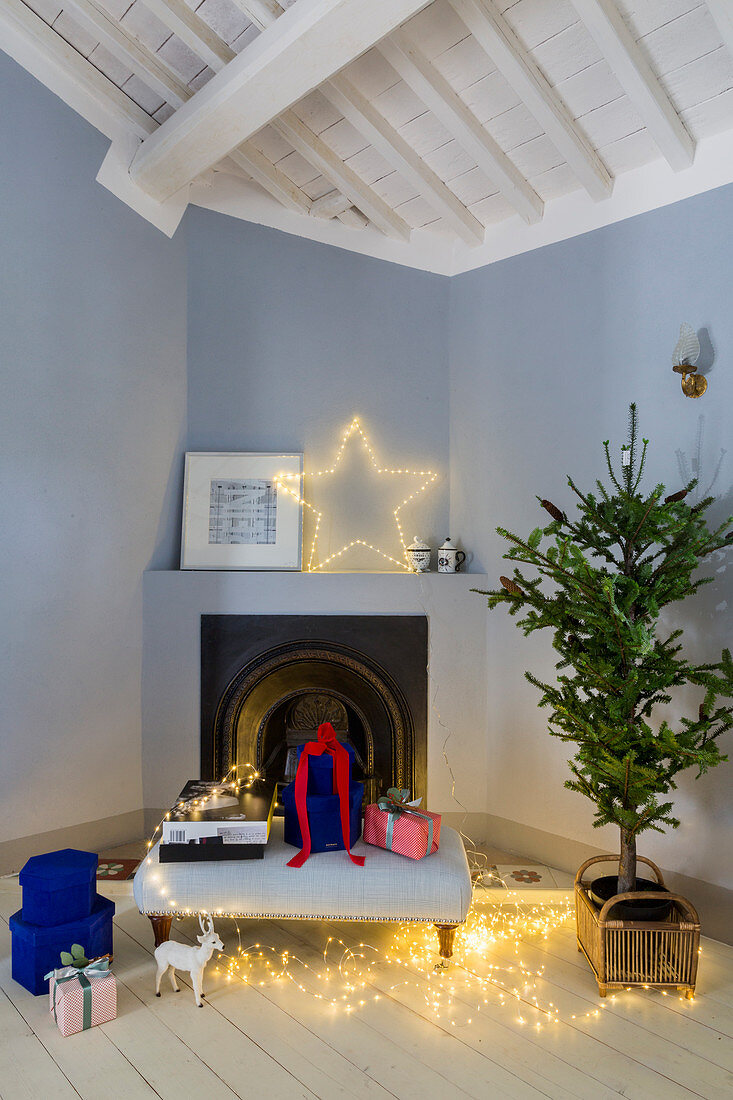 Weihnachtsdeko und Geschenke vorm Eckkamin in hellblauer Wand