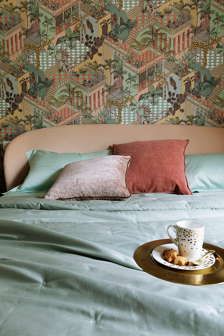 Golden plate and cup on bed against wallpaper with exotic pattern