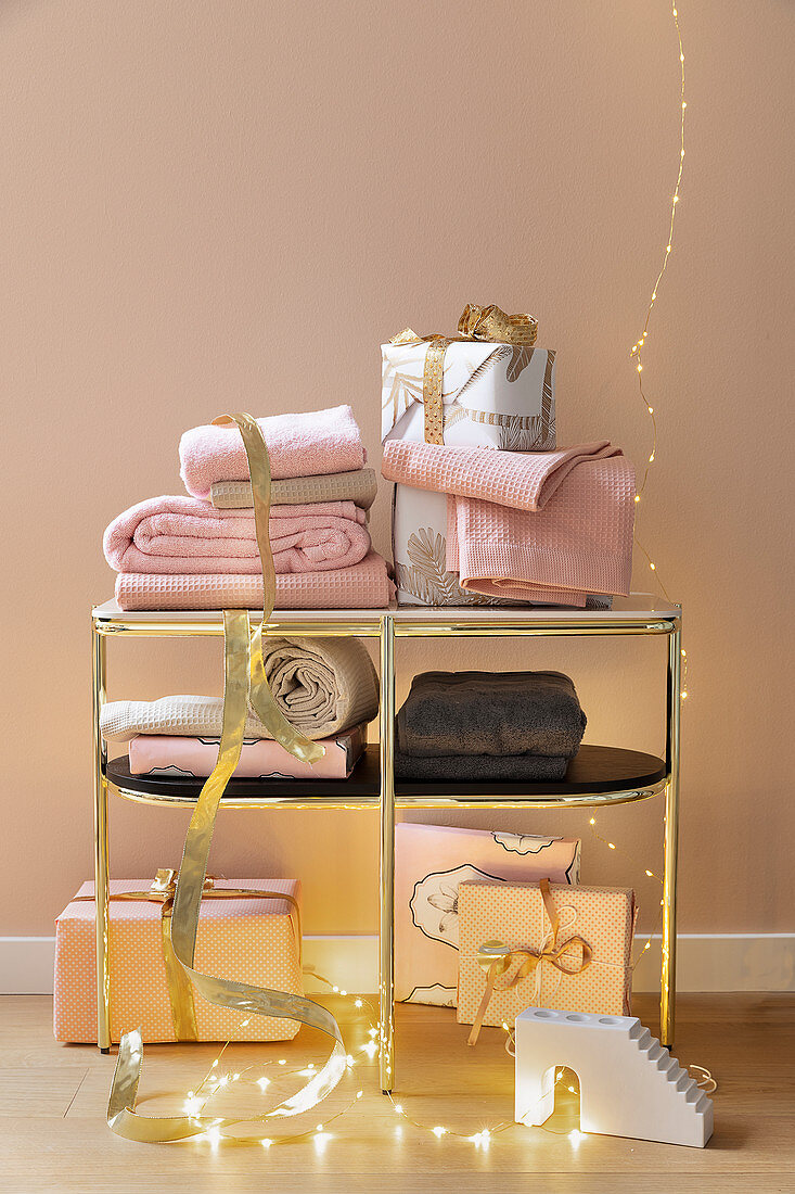 Handtücher und verpackte Geschenke auf goldenem Regal
