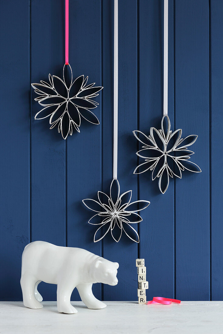 Snowflakes handmade from toilet roll tubes against blue board wall