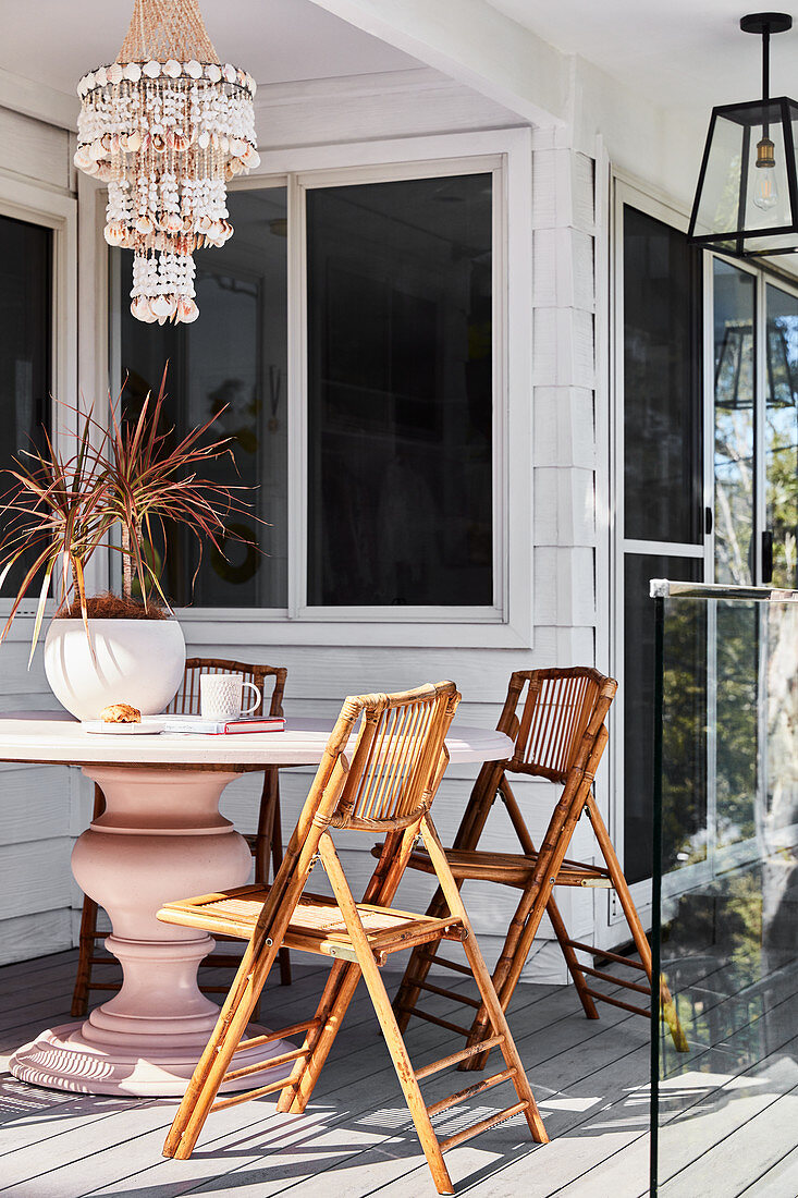 Rattan folding chairs around pink pedestal table on terrace