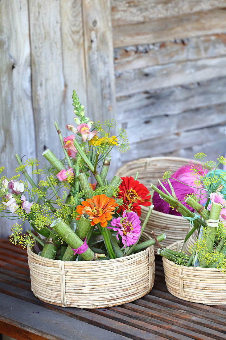 Arrangements of knotweed, snapdragons and zinnias in baskets