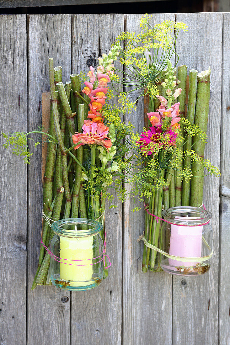 Candle lanterns made from knotweed, preserving jars and flowers hung on wooden fence