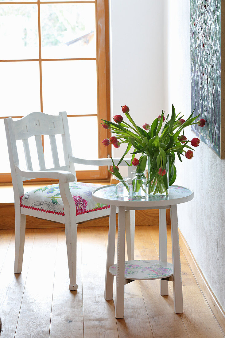 Redesing: Polsterstuhl mit floralem Stoffbezug, runder Tisch mit Tulpen