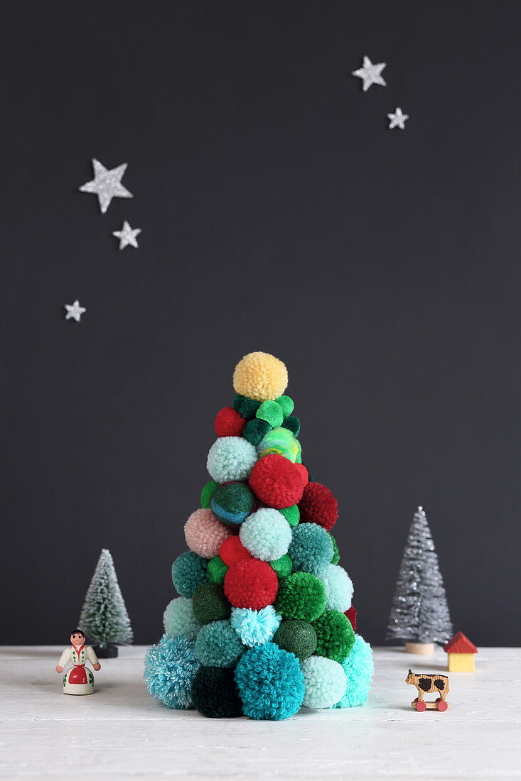Weihnachtsbaum aus bunten Pompons vor schwarzer Wand