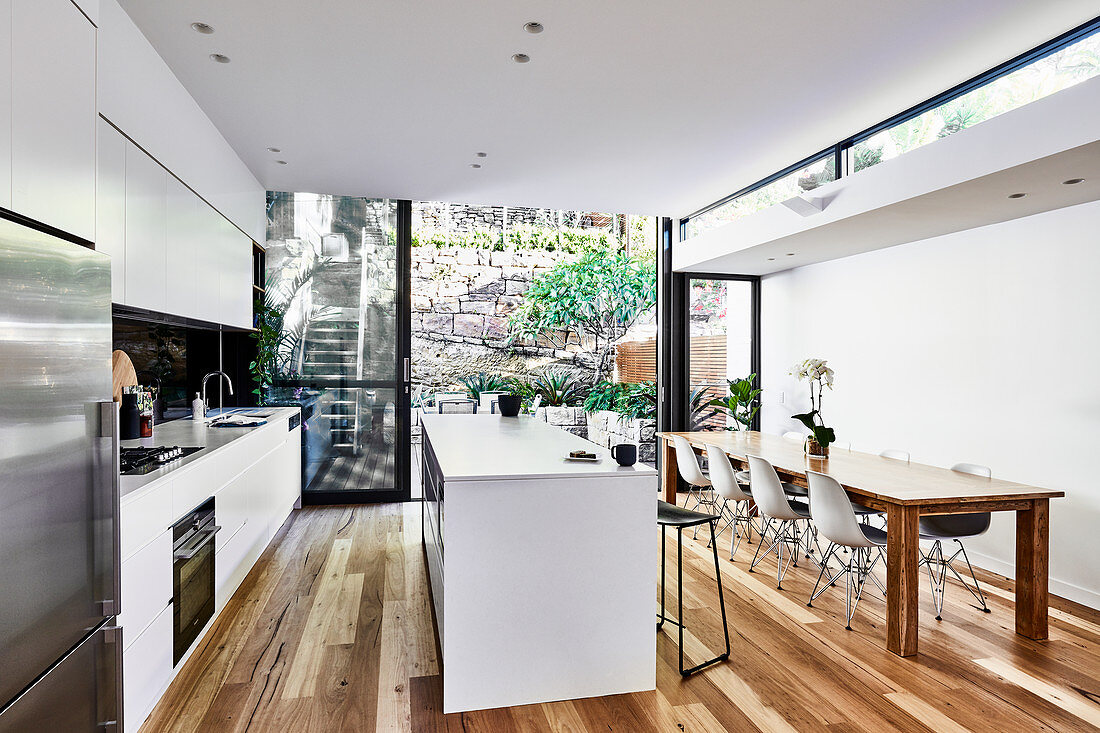 Moderner Wohnraum mit offener Küche und Glasfront zum Garten