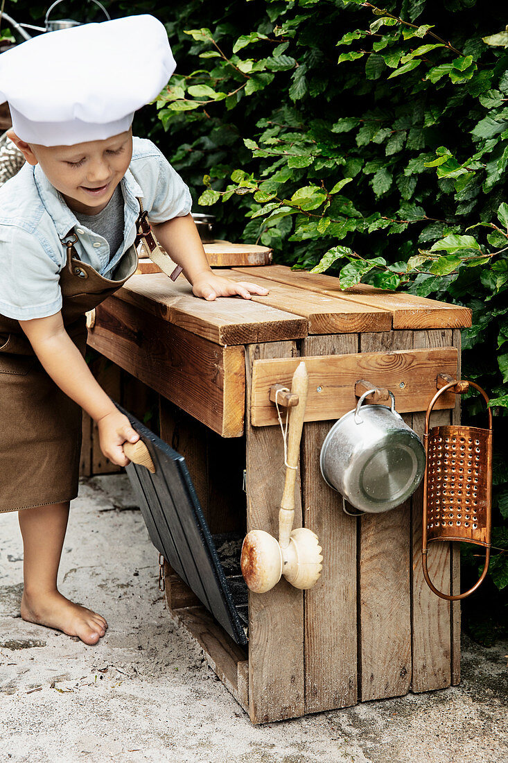 Little boy playing in DIY outdoor play kitchen