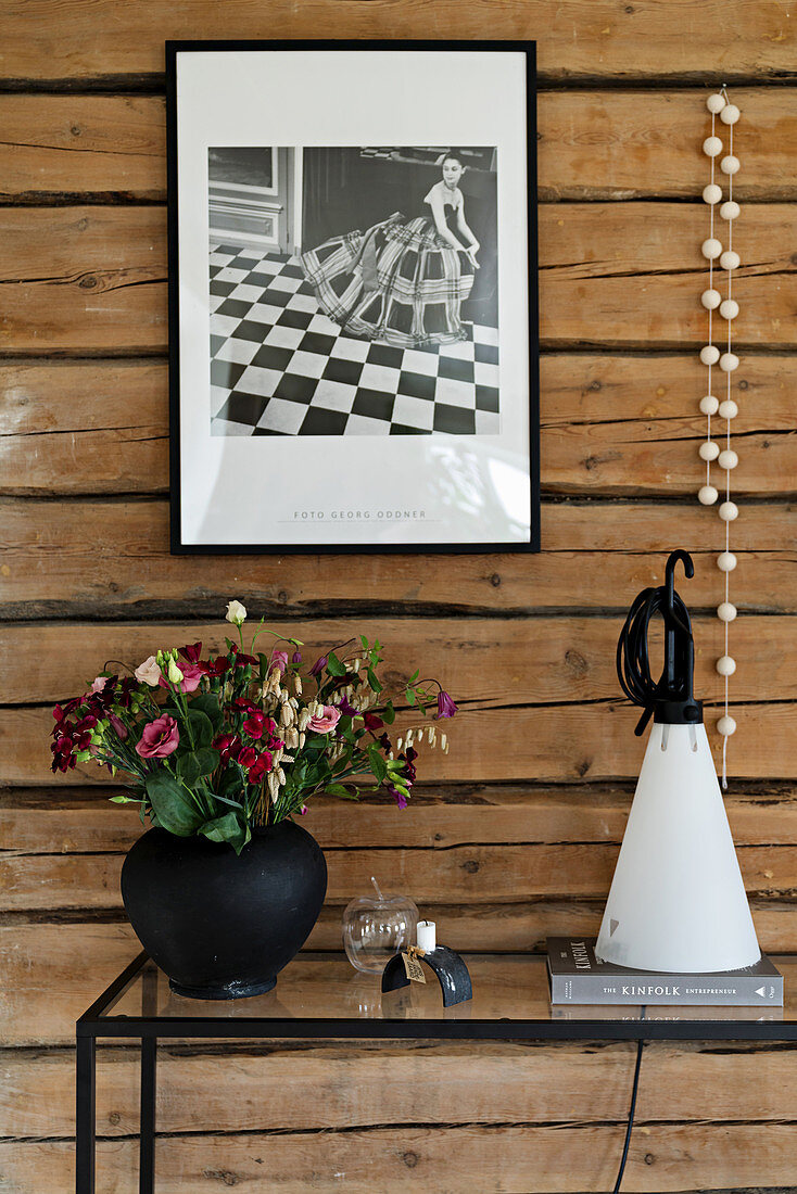 Black-and-white photo on rustic board wall above modern console table