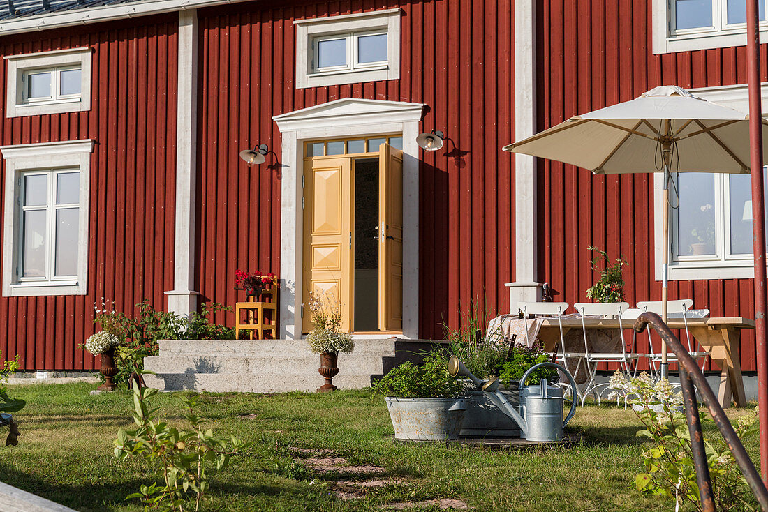 Gelbe offene Haustür im roten Schwedenhaus mit Vorgarten