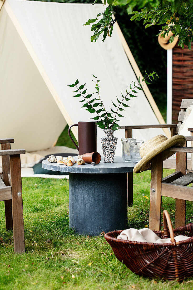 Grey table and wooden chairs in front of play tent in summery garden