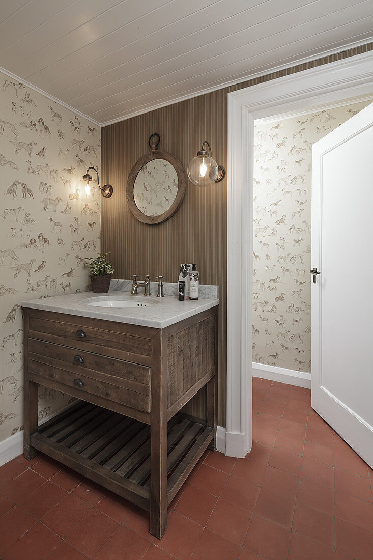 Washstand in corner of bathroom with patterned wallpaper