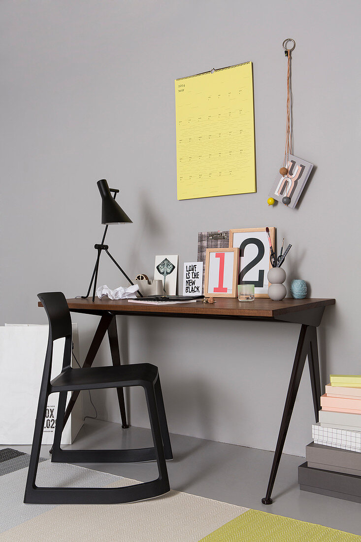 Bilderrahmen, Karten und Lampe auf Schreibtisch und schwarzer Holzstuhl
