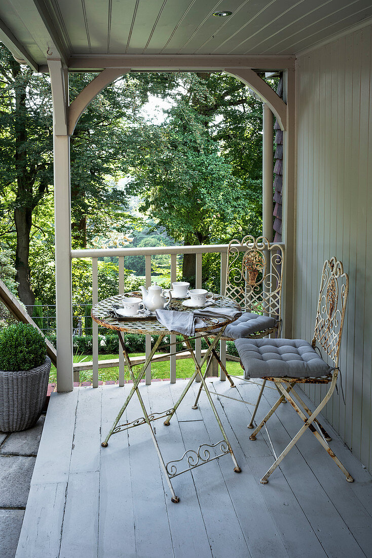 Schmiedeeiserner Tisch und Stühle auf viktorianischer Terrasse mit Gartenblick