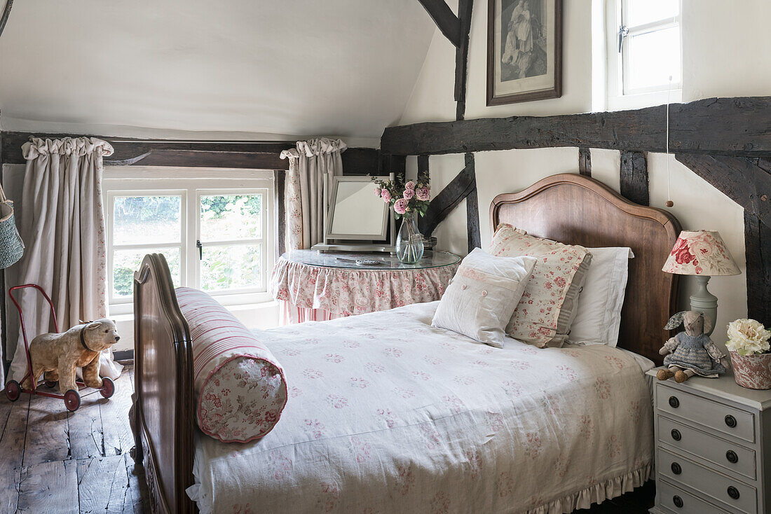 Vintage fabrics in room with antique French bed and original wooden floorboards and beams