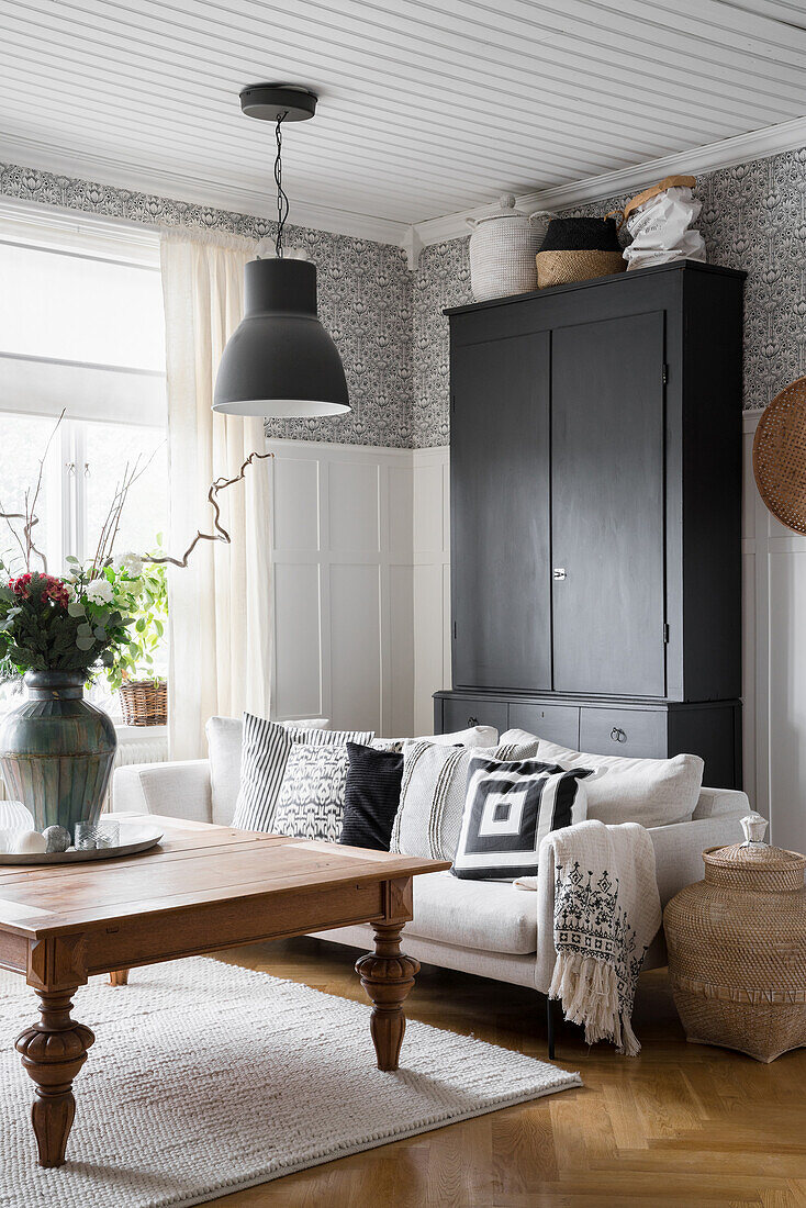 Black wardrobe, light-coloured upholstered sofa and wooden coffee table in the living room