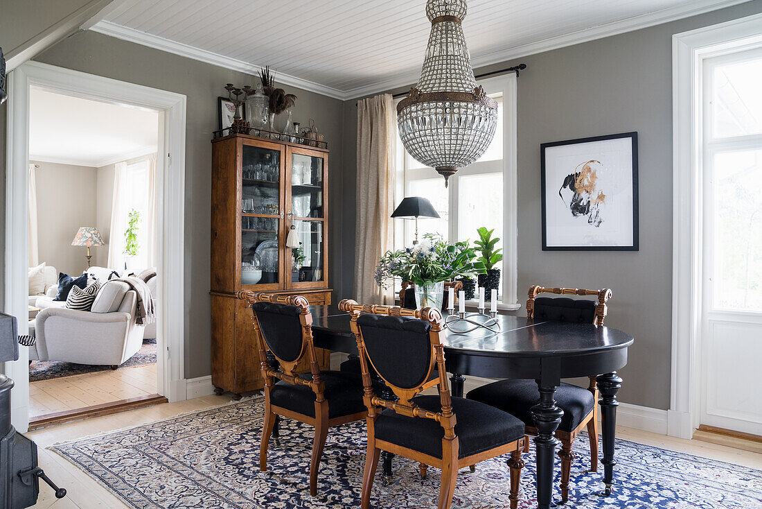 Black table with antique chairs and china cupboard in the dining room