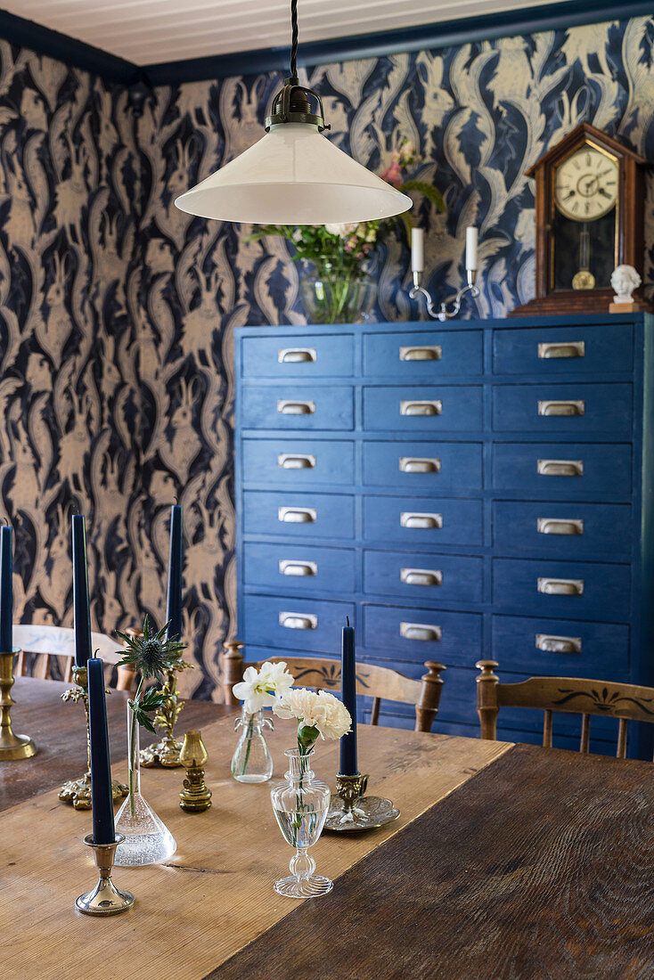 Blue chest of drawers in dining room with patterned wallpaper