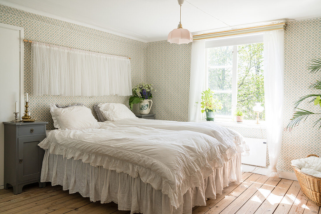 Doppelbett im Schlafzimmer mit nostalgischer Tapete, Vorhängen und Rüschen