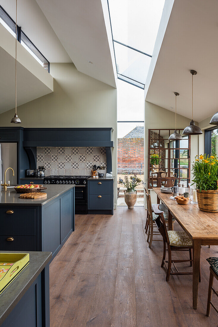 Open-plan kitchen with dark blue base units and rustic wooden dining table