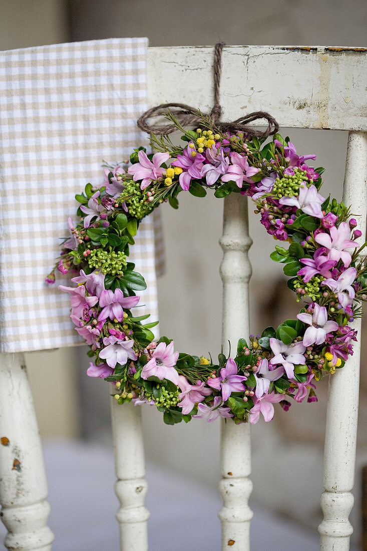 Frühlingskranz aus Hyazinthenblüten, Waxflower, Mimose und Buchs an Stuhllehne gebunden