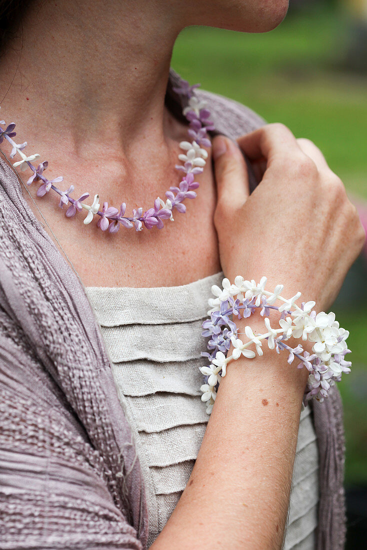 Woman wearing necklace and bracelet of threaded lilac florets
