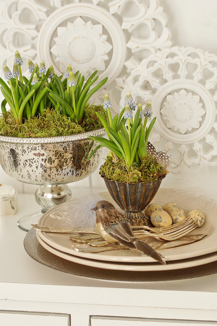 Easter decorations with grape hyacinths, Easter eggs, birds, and silver cutlery