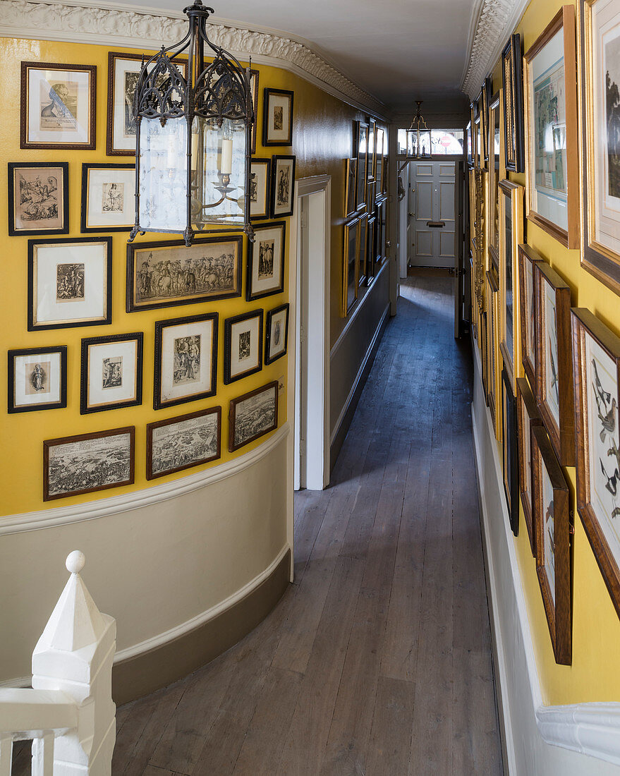 Gallery of pictures on curved yellow hallway wall