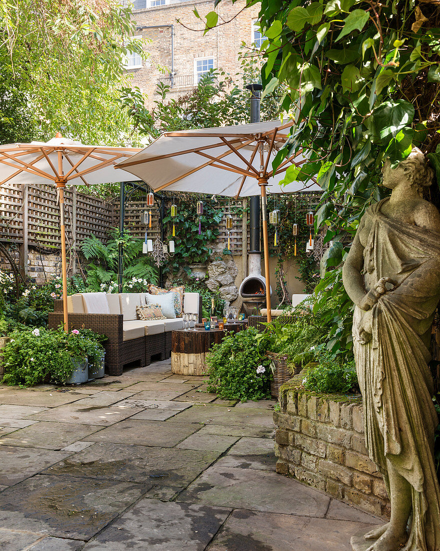 Statue, lounge furniture and parasols in courtyard garden