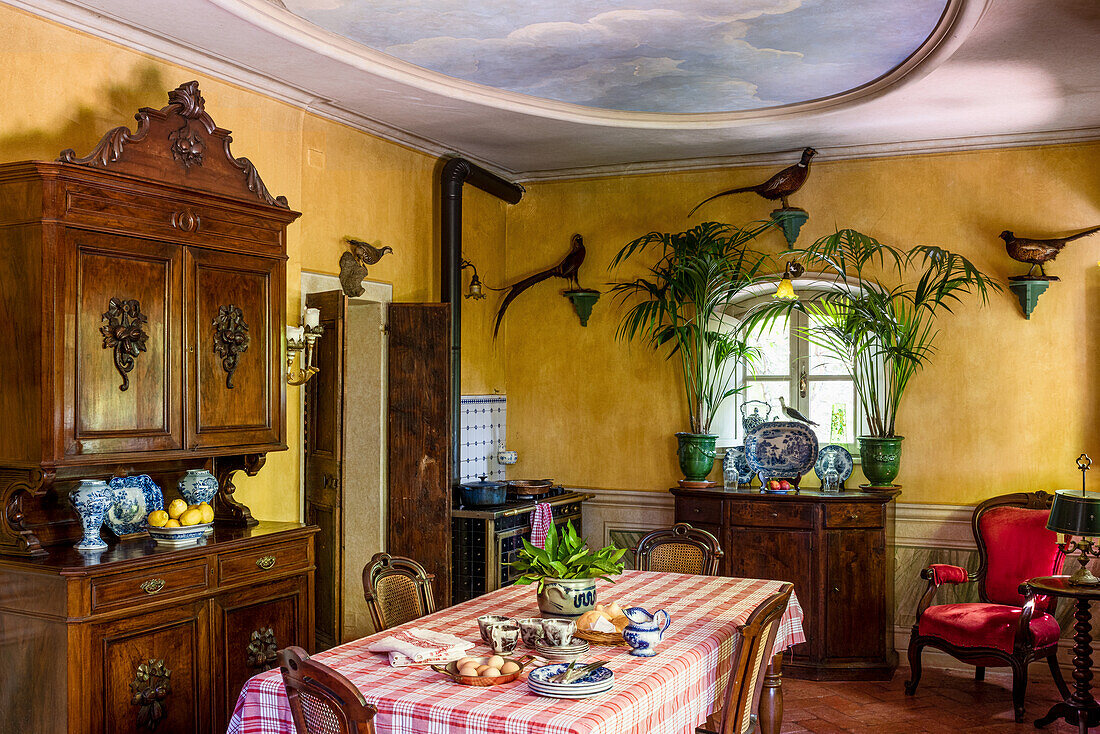Esstisch und antike Anrichte in Wohnküche mit gelben Wänden