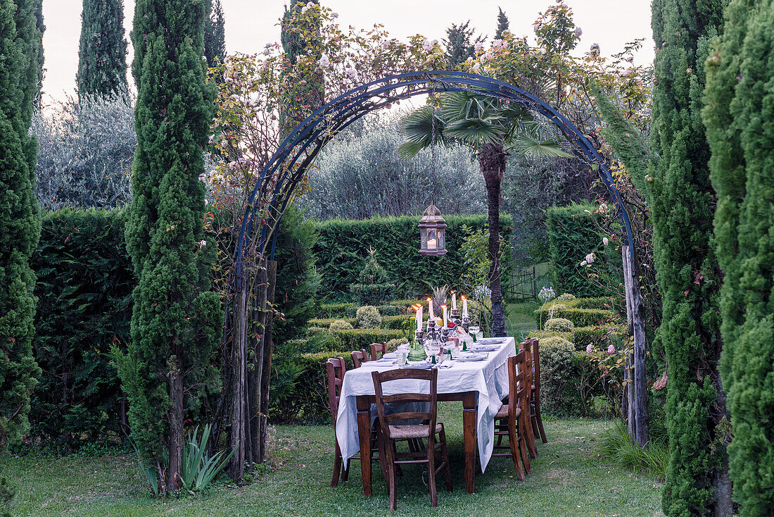 Festively set table and chairs under round arch in Renaissance garden
