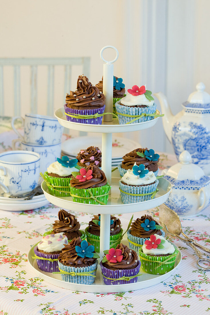 Cupcakes with colorful muffin liners and sugar flowers on a three-tiered dessert stand
