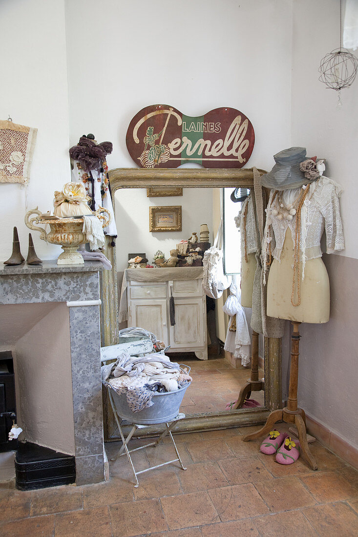 Tailor's dress form in front of a floor-length mirror with nostalgic decoration and junk