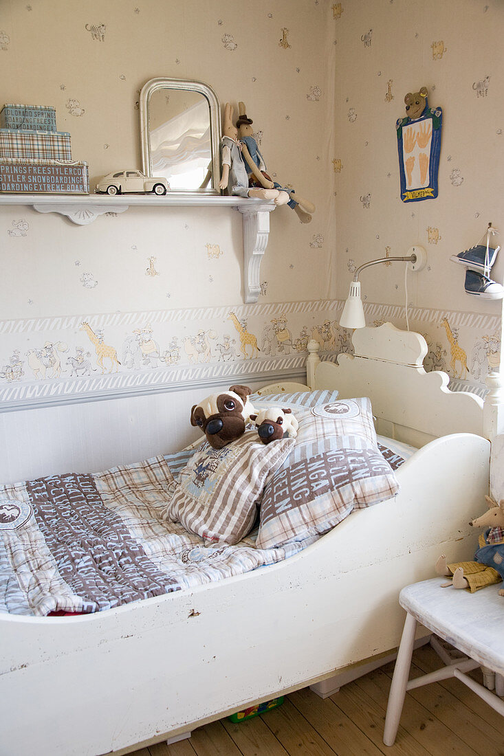 Old wooden sleigh bed in vintage-style child's bedroom with patterned wallpaper
