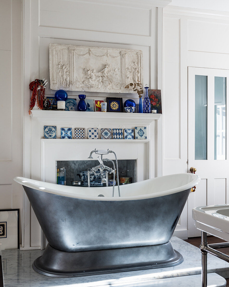Silver free-standing bathtub in classic bathroom with mantelpiece