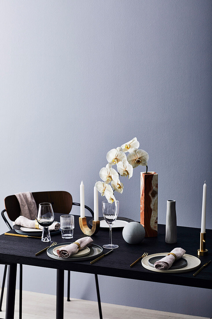 Gedeckter Tisch mit Vasen, Orchidee und Kerzen, darüber Pendelleuchte