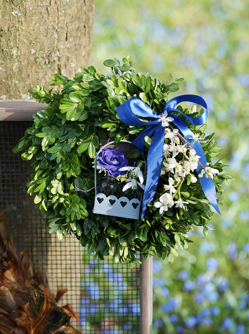 Buchskranz mit blauer Schleife und Blüten