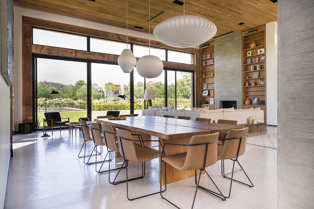 Upholstered chairs around dining table in large, open-plan interior with glass wall